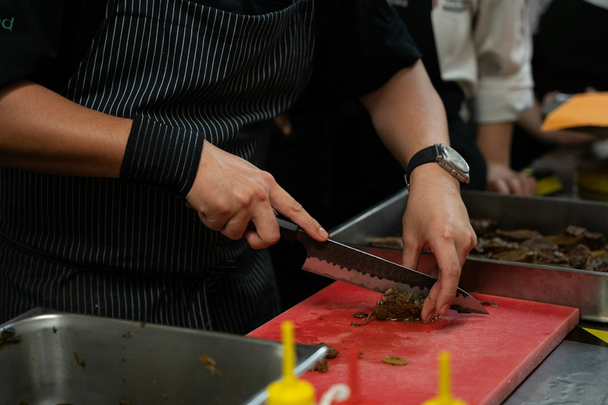 Chef chopping food on a red cutting board